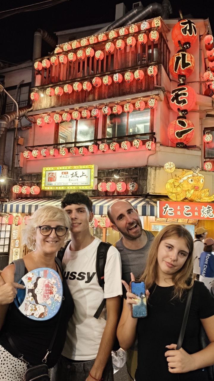 Foto familiar nocturna frente a un restaurante con faroles en Osaka