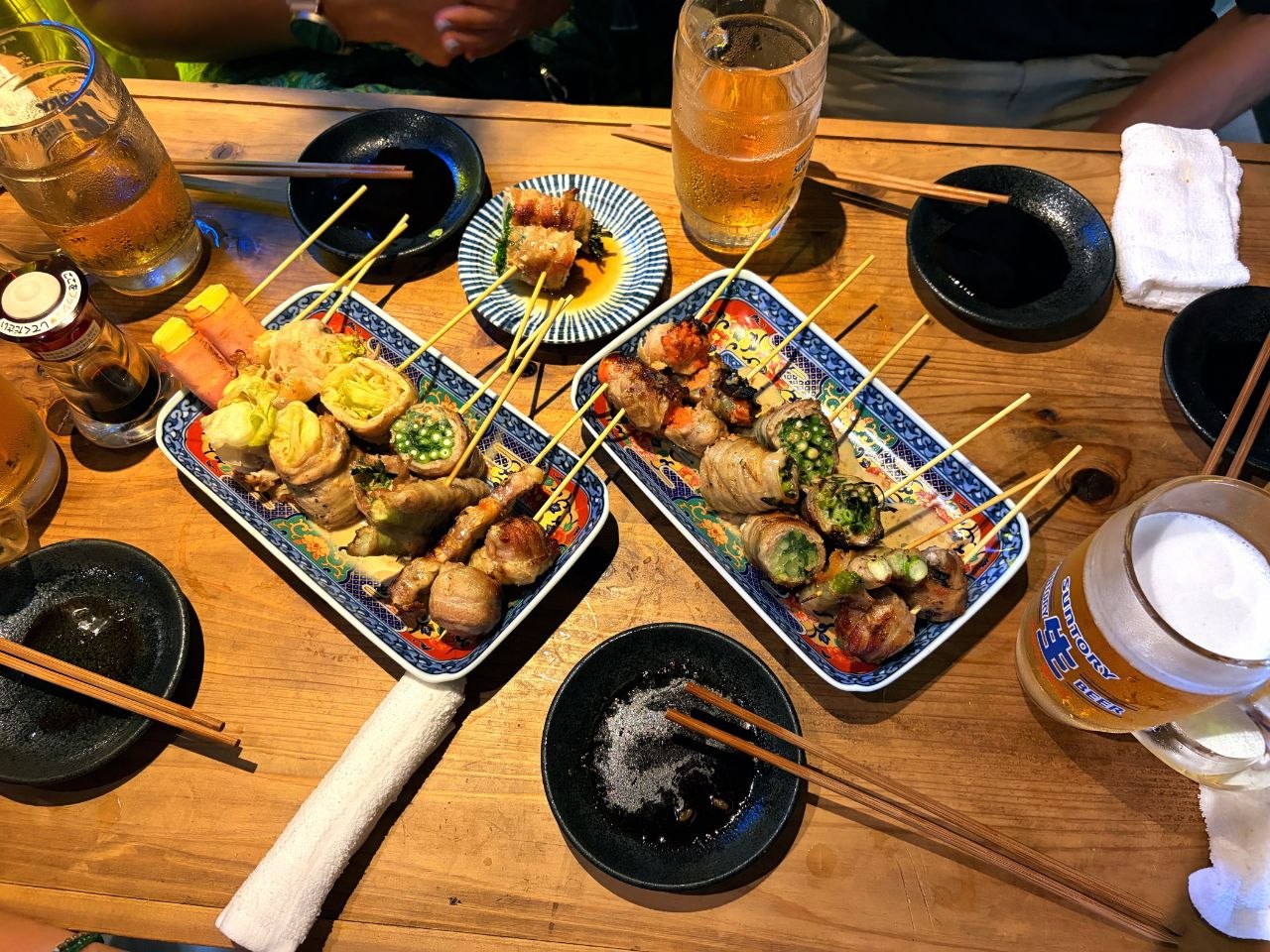 Mesa de izakaya en Nipponbashi con brochetas, cerveza y platos compartidos