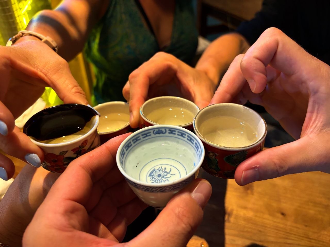 Brindis con vasos pequenos de sake sobre una mesa de madera