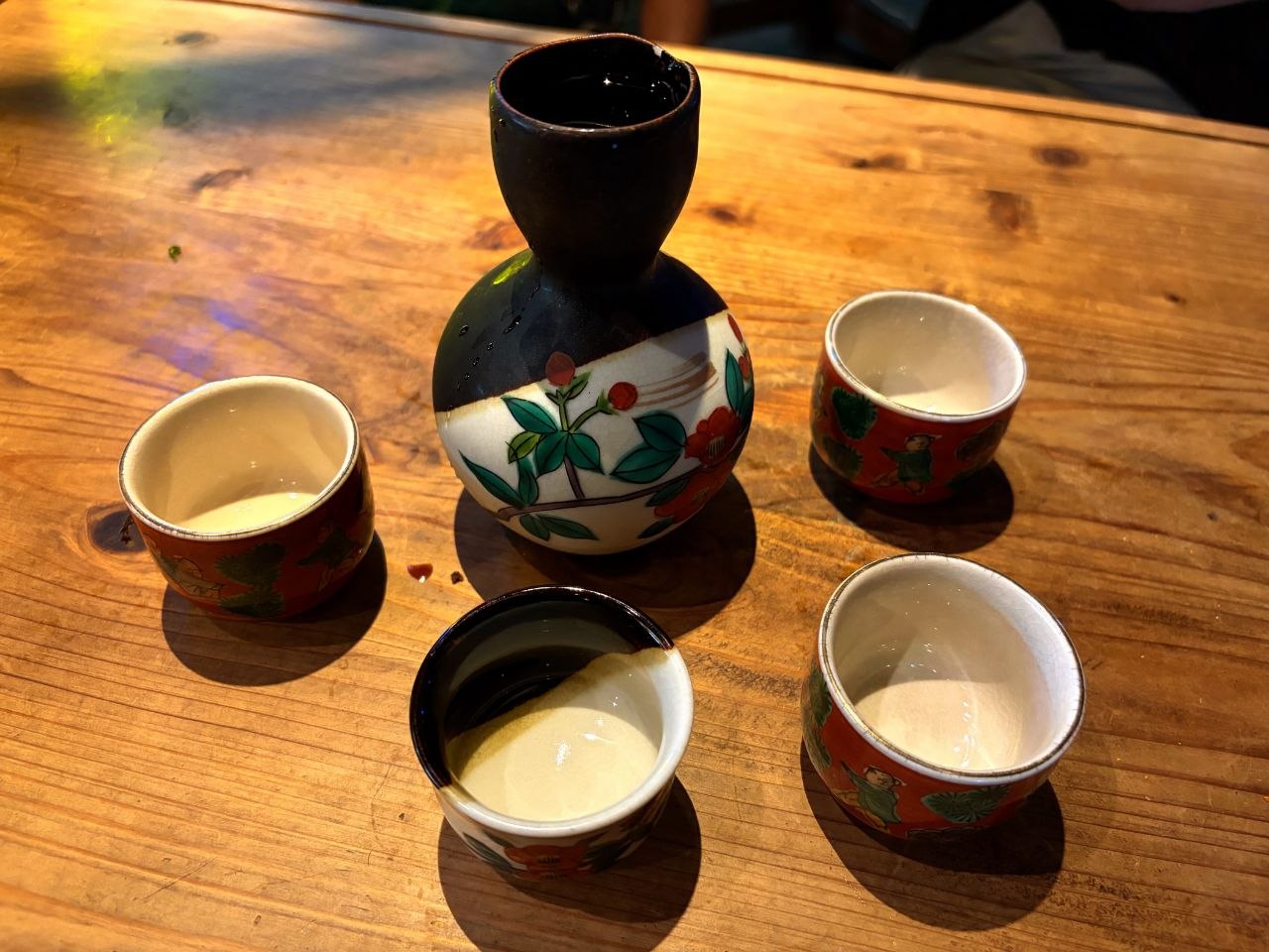 Botella y vasos de sake vacios sobre una mesa de madera