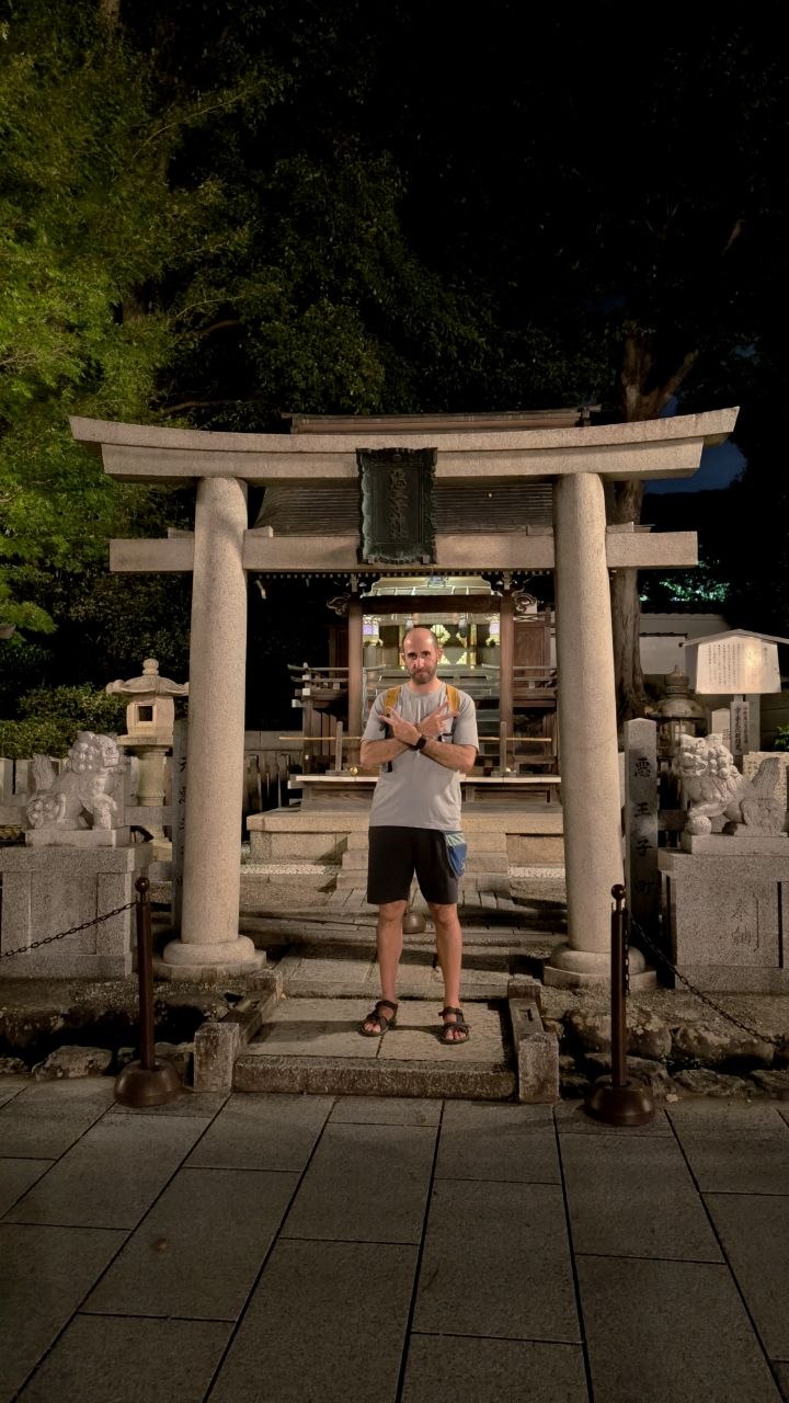 Retrato bajo un torii de piedra en un pequeno santuario nocturno de Gion