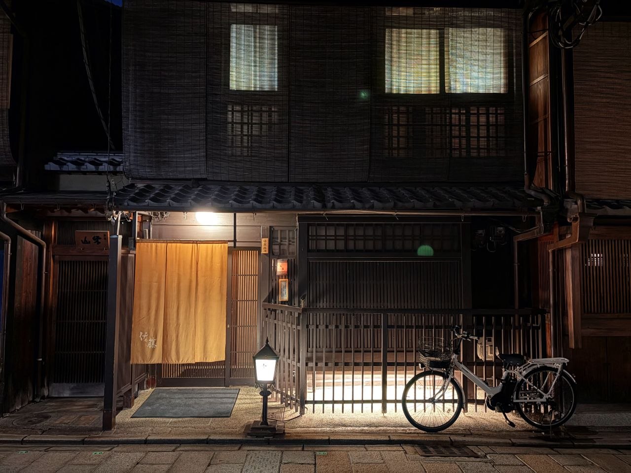 Fachada tradicional de restaurante en Gion con cortina amarilla y bicicleta