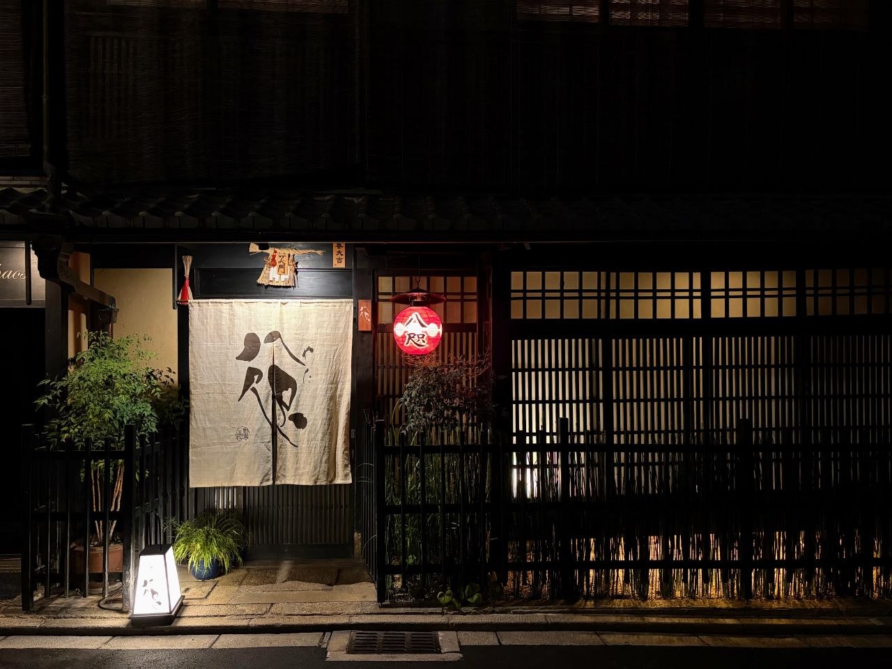 Entrada tradicional de Gion con noren y farol rojo iluminado