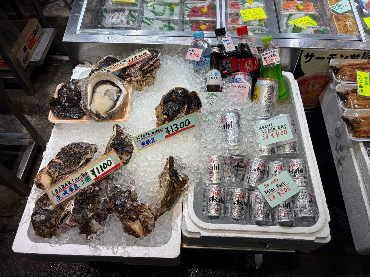Ostras sobre hielo junto a bebidas frias y cerveza Asahi en Nishiki Market