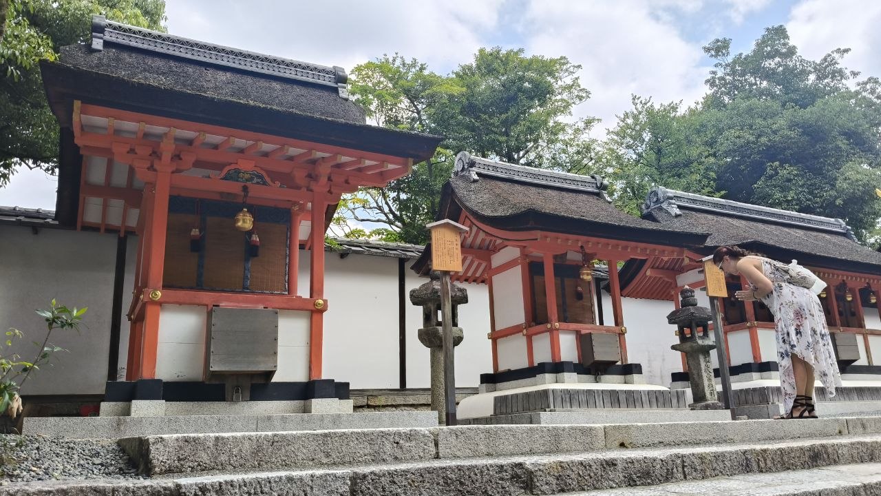 Edificios rojos de Fushimi-Inari Taisha con una visitante haciendo una reverencia