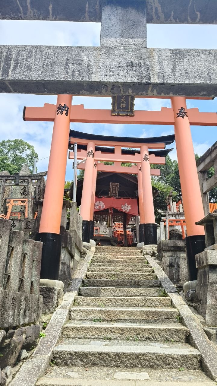 Escalinata de piedra hacia un santuario entre torii rojos en Fushimi-Inari
