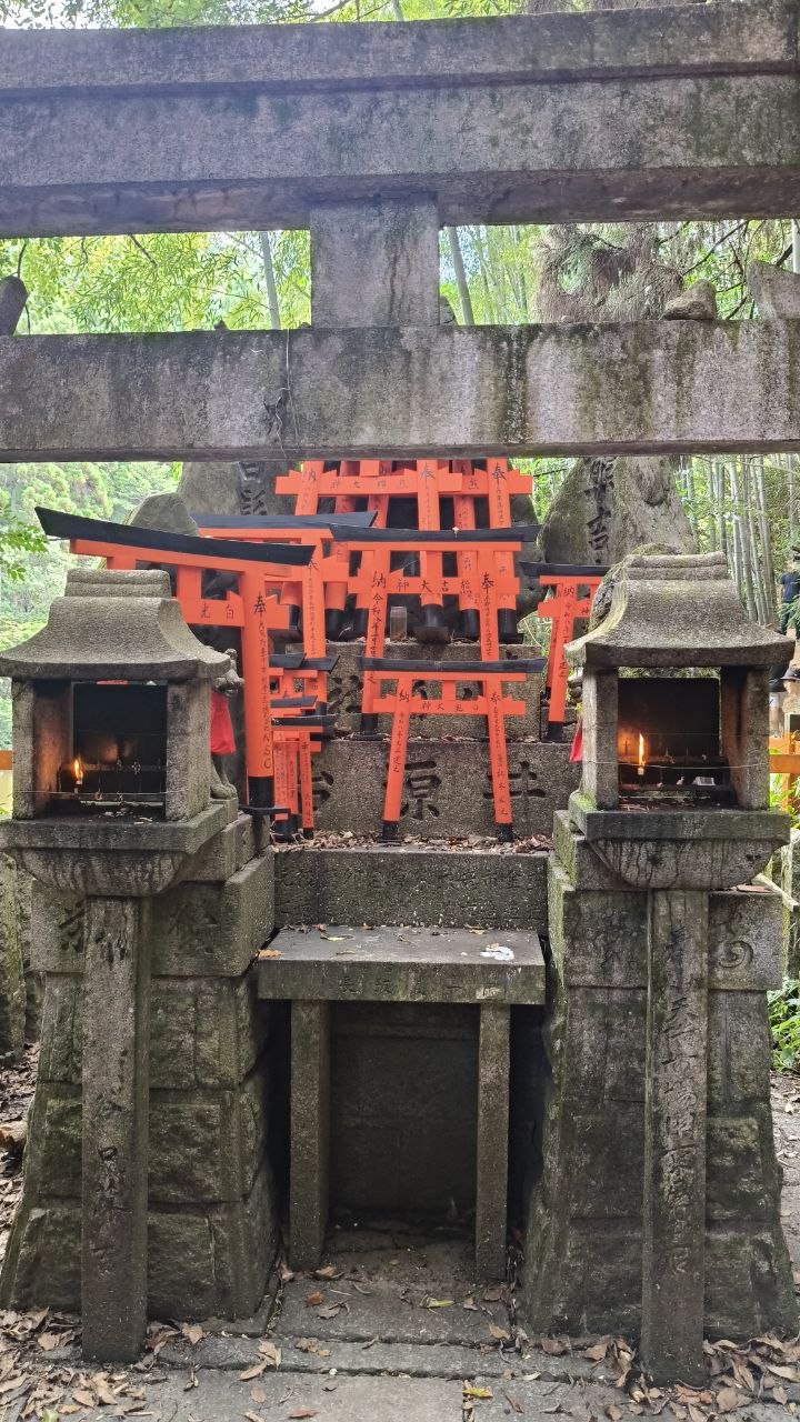 Altar de piedra con pequenos torii rojos y faroles encendidos en Fushimi-Inari