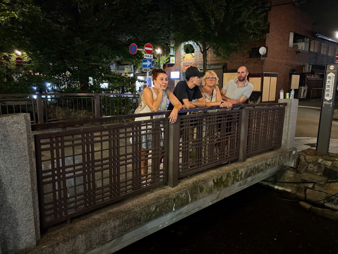 Grupo apoyado en un puente junto al canal de Pontocho de noche