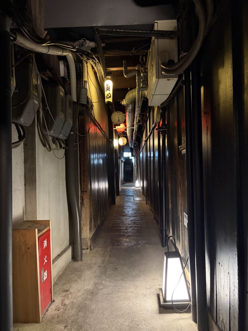 Pasillo estrecho de Pontocho con faroles y tuberias vistas sobre fachadas oscuras