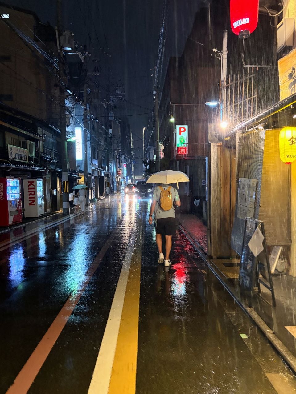 Vuelta al hotel por una calle mojada de Kyoto bajo paraguas