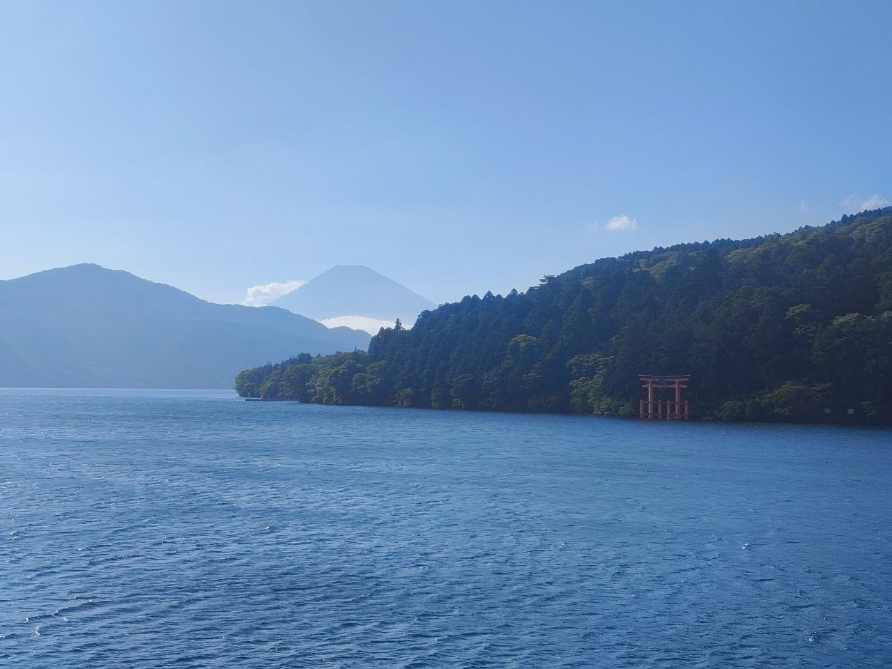 Vista amplia del lago Ashi con el torii rojo junto a la orilla